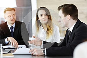 Business people or lawyers discussing questions at meeting in sunny office. Unknown businessman and woman with colleague