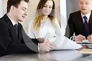 Business people or lawyers discussing questions at meeting in sunny office. Unknown businessman and woman with colleague