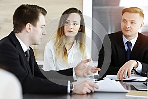 Business people or lawyers discussing questions at meeting in sunny office. Unknown businessman and woman with colleague