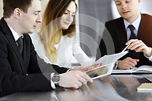 Business people or lawyers discussing questions at meeting in sunny office. Unknown businessman and woman with colleague