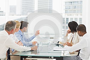 Business people looking at blank whiteboard in conference room