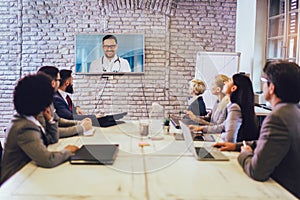 Business people looking doctor speech at projector screen in video conference