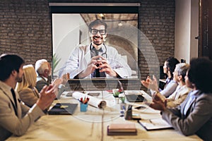 Business people looking doctor speech at projector screen in video conference