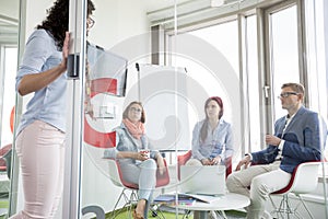 Business people looking at female colleague standing in sliding door