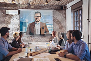 Business people looking at projector during video conference photo