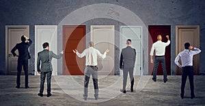 Business people looking to select the right door. Concept of confusion and competition