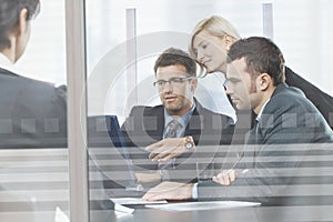 Business people meeting in boardroom behind glass
