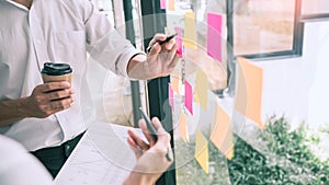 Business people meeting at office and use sticky notes on glass wall in office, diverse employees people group planning work