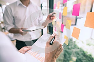 Business people meeting at office and use sticky notes on glass wall in office, diverse employees people group planning work