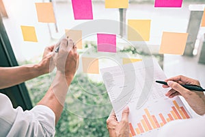 Business people meeting at office and use sticky notes on glass wall in office, diverse employees people group planning work