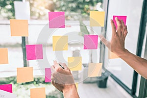 Business people meeting at office and use sticky notes on glass wall in office, diverse employees people group planning work