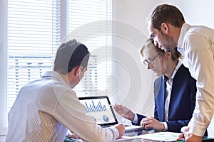 Business people meeting to discuss key performance indicators of sales or operations report with laptop and charts in office