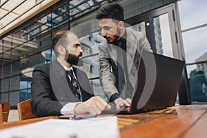 business people meets outdoors. Two men are using a laptop. Working break. Team and business support. Collaboration and