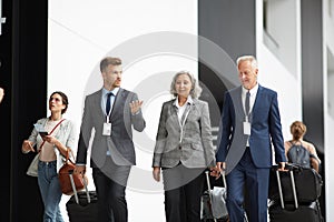 Business people moving along airport with suitcases
