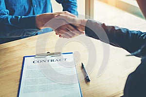 Business people negotiating a contract handshake between two col