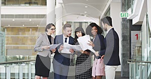 Business people in an office reading paperwork together. A group of colleagues comparing scores and ratings for success