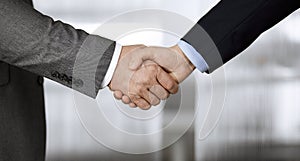 Business people in office suits standing and shaking hands, close-up. Business communication concept. Handshake and