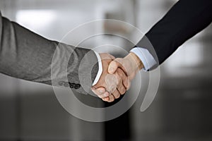 Business people in office suits standing and shaking hands, close-up. Business communication concept. Handshake and