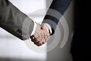 Business people in office suits standing and shaking hands, close-up. Business communication concept. Handshake and