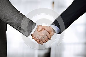 Business people in office suits standing and shaking hands, close-up. Business communication concept. Handshake and