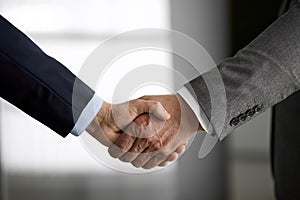 Business people in office suits standing and shaking hands, close-up. Business communication concept. Handshake and