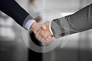 Business people in office suits standing and shaking hands, close-up. Business communication concept. Handshake and