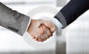 Business people in office suits standing and shaking hands, close-up. Business communication concept. Handshake and