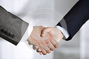 Business people in office suits standing and shaking hands, close-up. Business communication concept. Handshake and