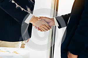 Business people in office suits standing and shaking hands, close-up. Business communication concept. Handshake and marketing