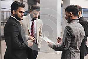 Business people outdoor meeting. A group of business people meet outdoors. Male employees in suits communicate outdoors