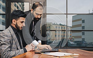 Business people outdoor meeting. A group of business people meet outdoors. Two men are using a laptop. Working break