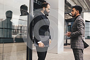 Business people outdoor meeting. Two men in suits are standing and talking to each other. Working break. Friendly