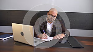 Business, people, paperwork and technology concept - businessman with laptop computer and papers working at office