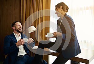 Business people, partners having a nice conversation over a cup of coffee while relaxing in a hotel room after successful