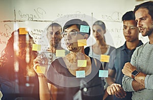Business people planning ideas on a glass board thinking, brainstorming and working on strategy for a project. Smart