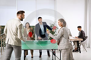 Business people playing ping pong in office