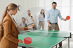 Business people playing ping pong in office