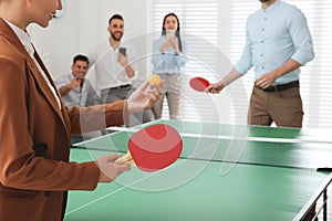 Business people playing ping pong in office, focus on tennis racket. Space for text