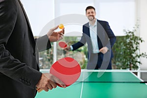 Business people playing ping pong in office, focus on racket