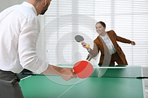 Business people playing ping pong in office, focus on tennis racket. Space for text