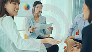 Business people proficiently discuss work project while sitting in circle