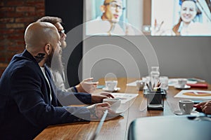 Business people, project managers having online conference video call on tv screen with diverse company employees