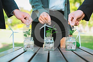 Business people put coin to money saving glass jar. Gyre