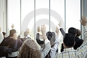 Business people raising hand up to ask question with speaker in seminar conference  raise hands up to agree or vote for comments photo