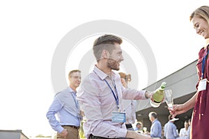 Smiling mature businessman looking at colleagues talking during success party on terrace