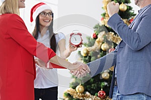 Business people shake hands on background of New Year tree