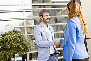 Business people shake hands in front of the office building