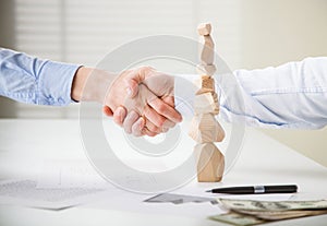 Business people shake hands near built wooden tower