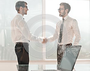 Business people shake hands standing in a bright office