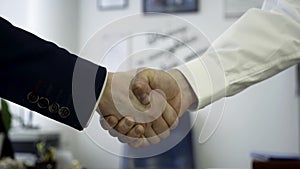 Business people shaking hands as a sign of agreement. Close up for firm handshake of two business partners in the office